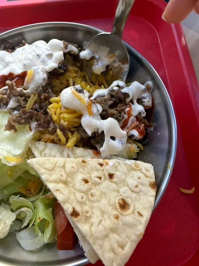 Gyro platter drizzled with white sauce and hot sauce