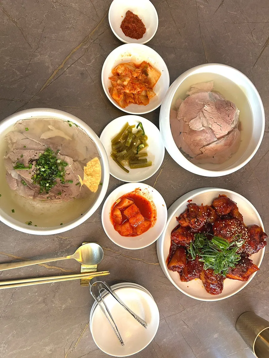 Table setting with gomtang, Pyongyang naengmyeon, and braised tail