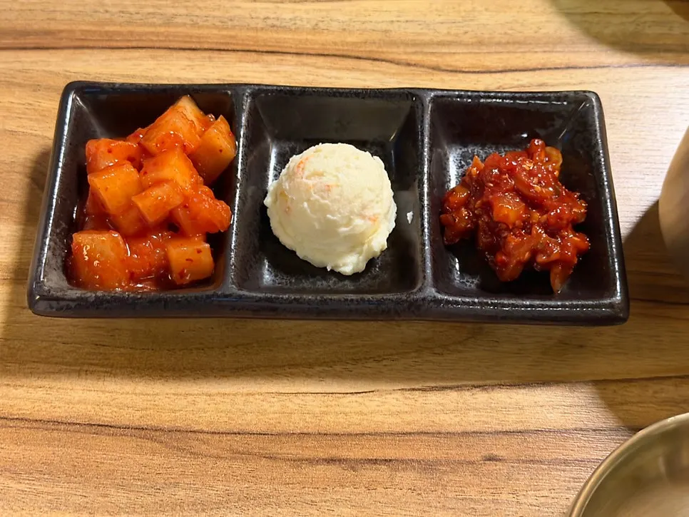 Three side dishes: potato salad, salted seafood, and diced radish kimchi