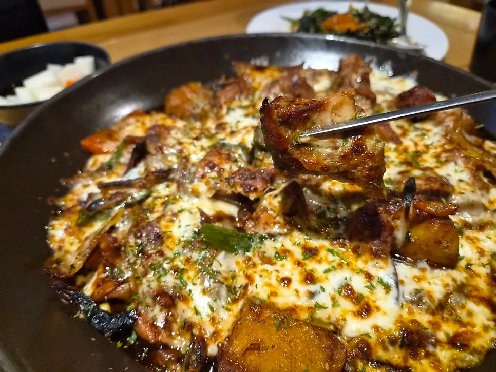 A bite of jjimdak coated in cheese and soy sauce