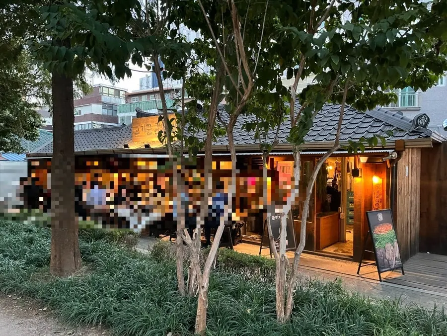 Outdoor terrace seating at Gogikkun Gimchunbae Hongdae Supgil next to Gyeongui Line Forest Park