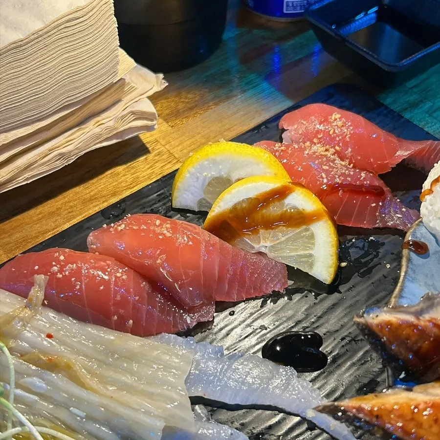 A bite-sized piece of long-tail salmon sushi held up