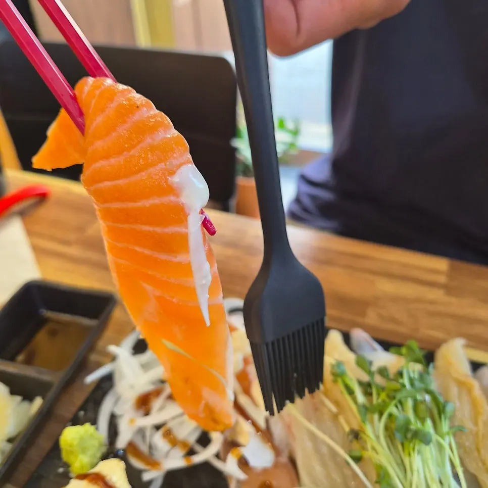 Extra-long salmon sushi compared with the brush length