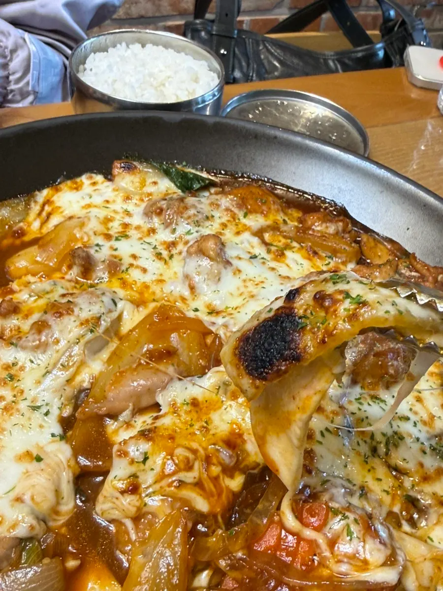 A piece of gochujang jjimdak wrapped in cheese