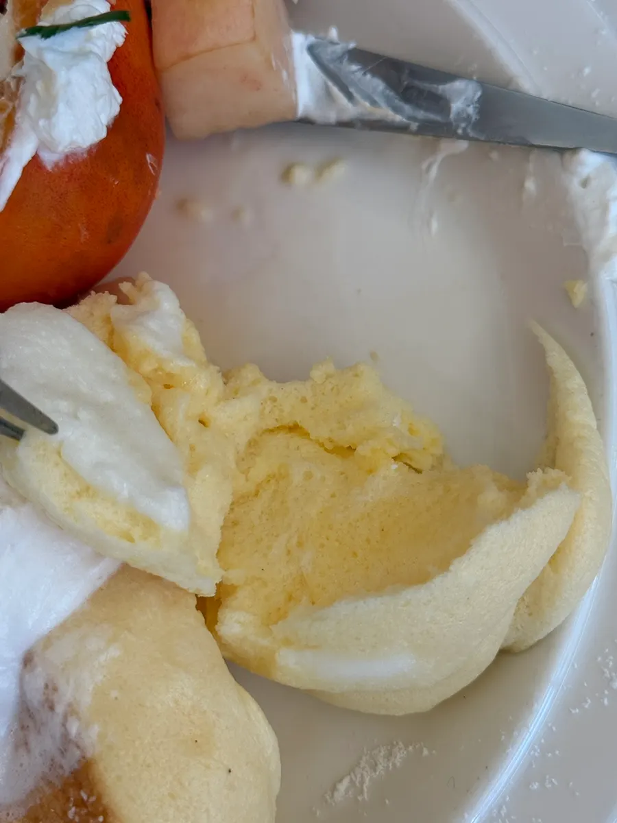 A bite of soufflé scooped up with whipped cream