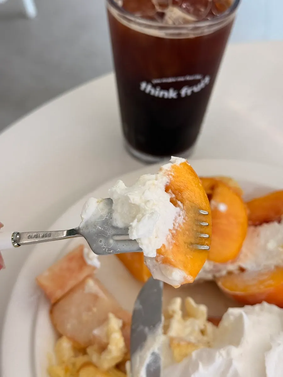 A scoop of Greek yogurt from inside the whole peach