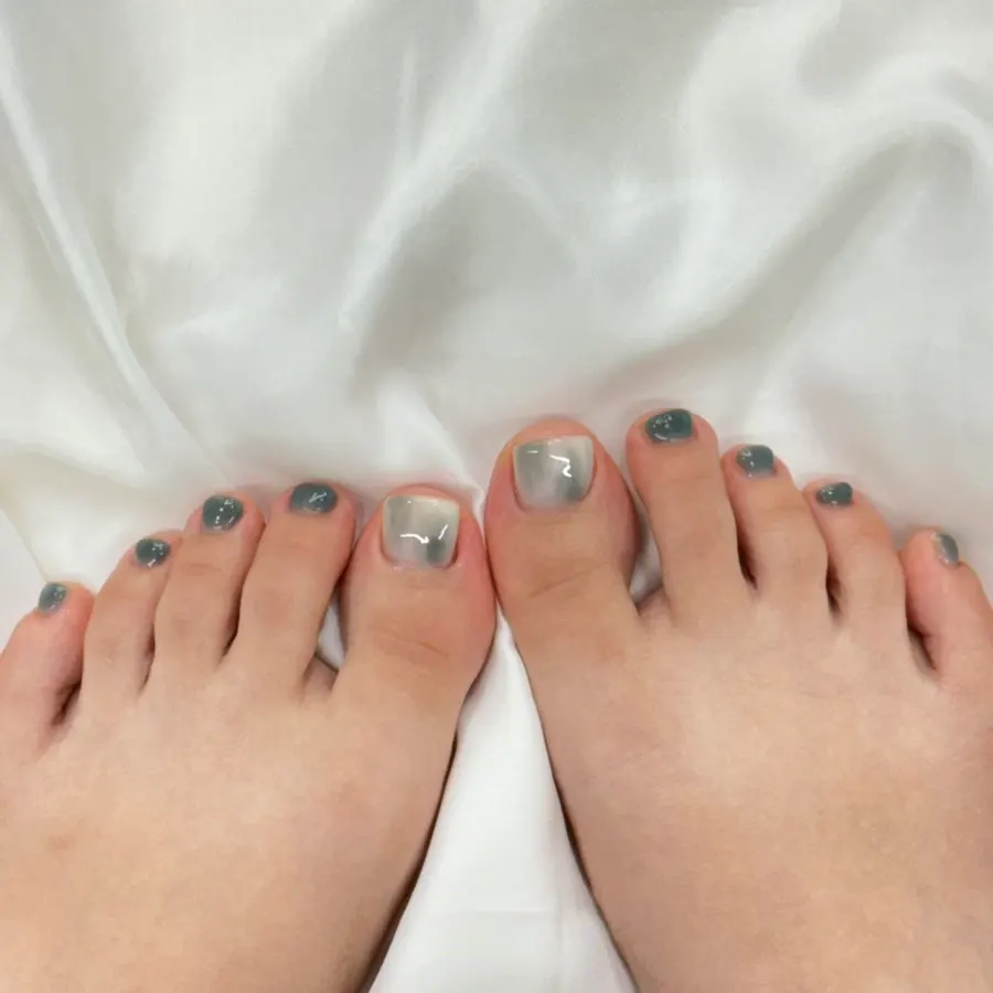 Finished pedicure with silver design on the big toe and green-blue color