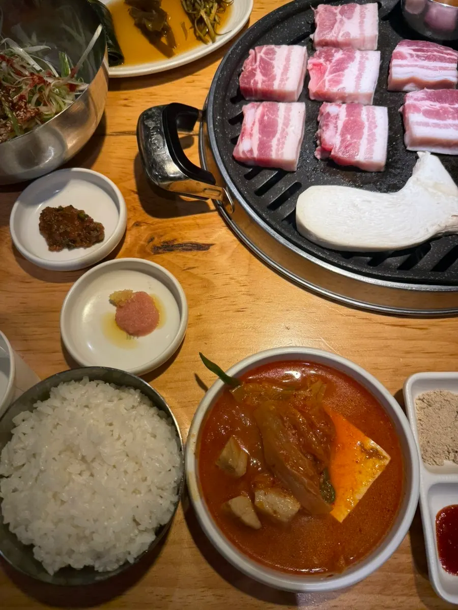 Table spread with grilling ogyeopsal and kimchi jjigae