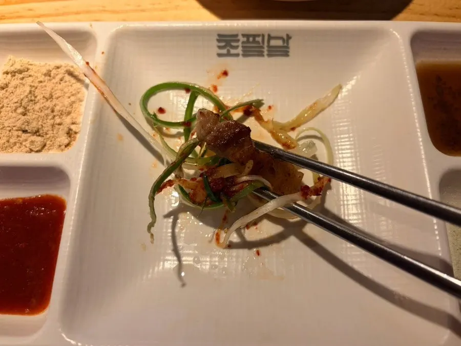 A piece of ogyeopsal topped with scallion salad