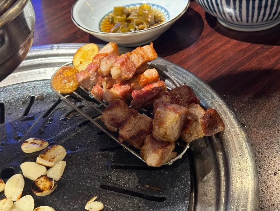 비빔국수를 돌돌 말아 고기와 먹는 장면