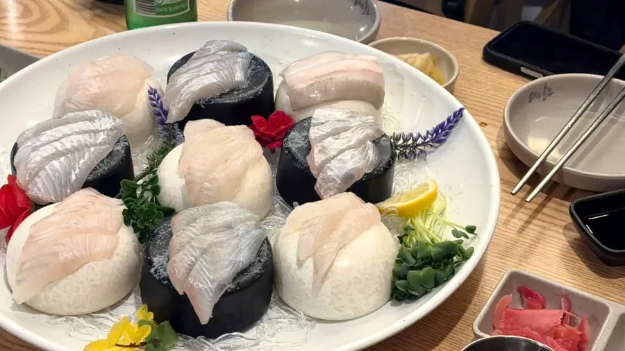 A plate of sashimi with a soju glass