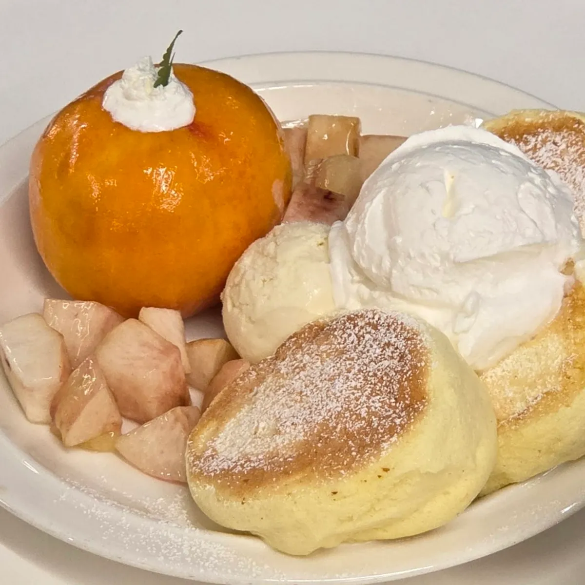 A plate piled with fresh peach and soufflé pancake