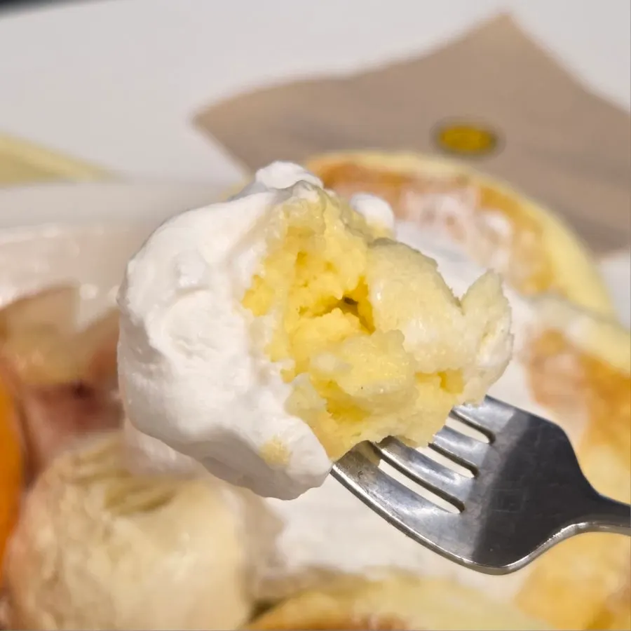 A bite of soufflé topped with whipped cream and peach