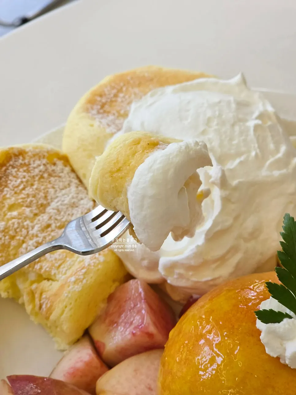A bite of peach soufflé dipped in fresh cream