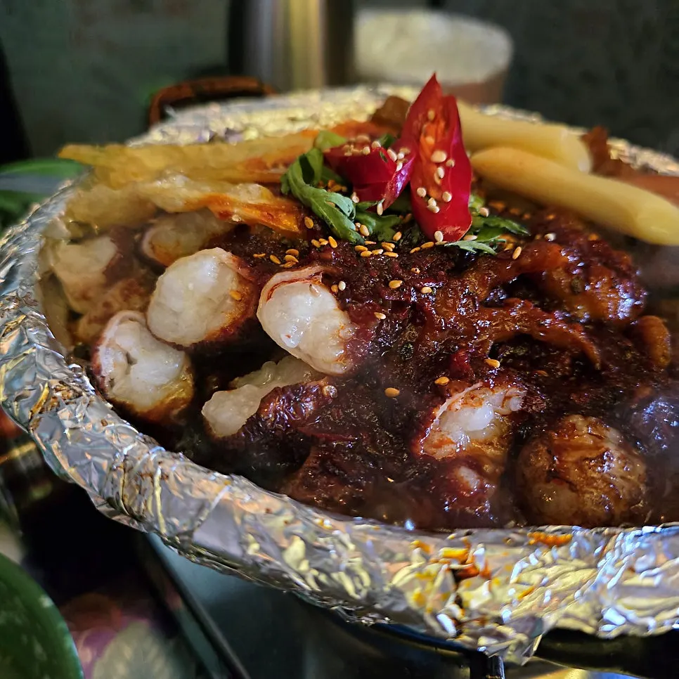Pot of soup chicken feet with rice cake, sausage, and quail egg toppings