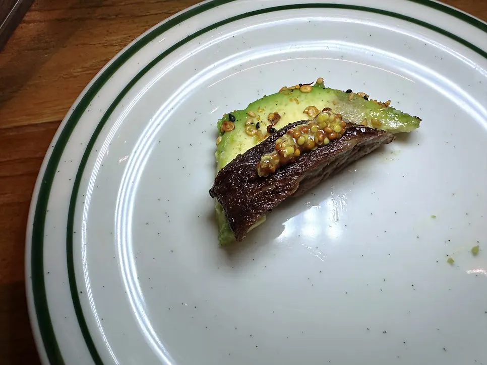 A bite of meat topped with avocado