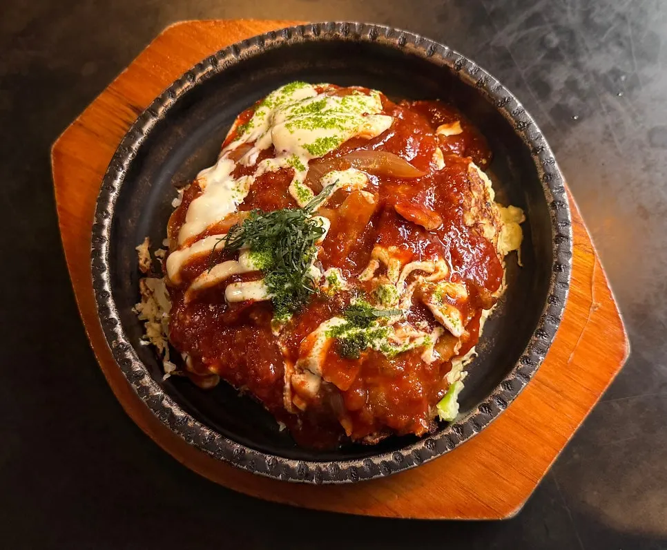 Okonomiyaki topped with tomato sauce and mayonnaise