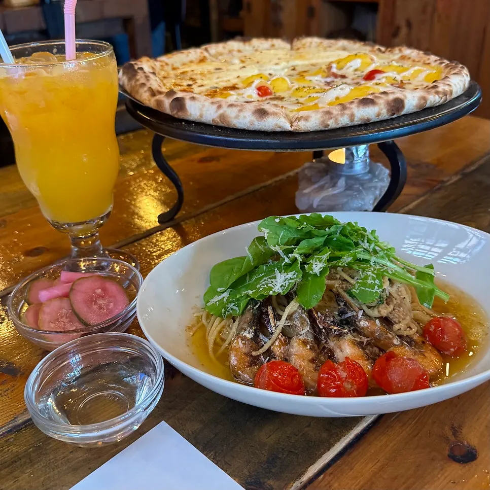 Half-and-half wood-fired pizza and oil pasta spread on the table