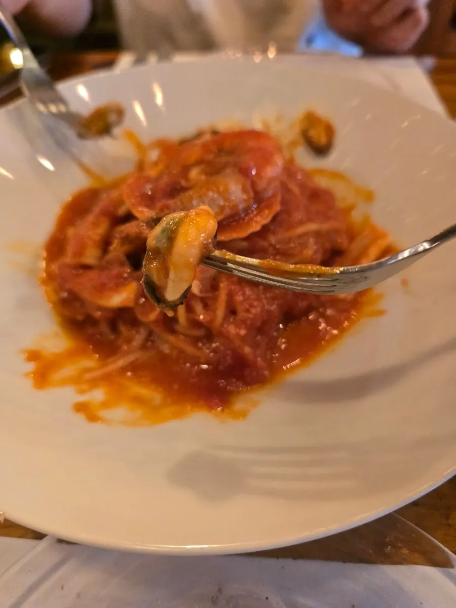Fork lifting up seafood tomato pasta noodles