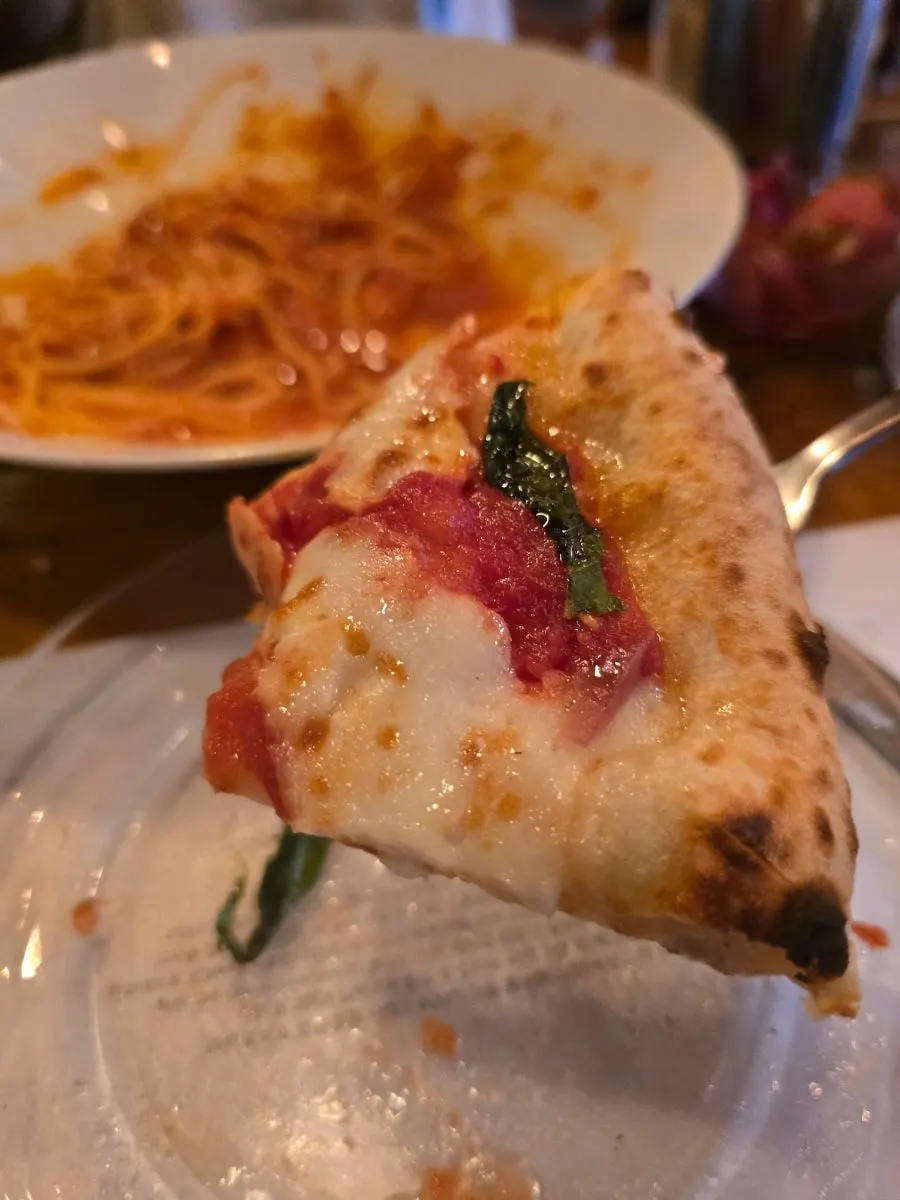 Slice of wood-fired pizza lifted up with stretchy cheese