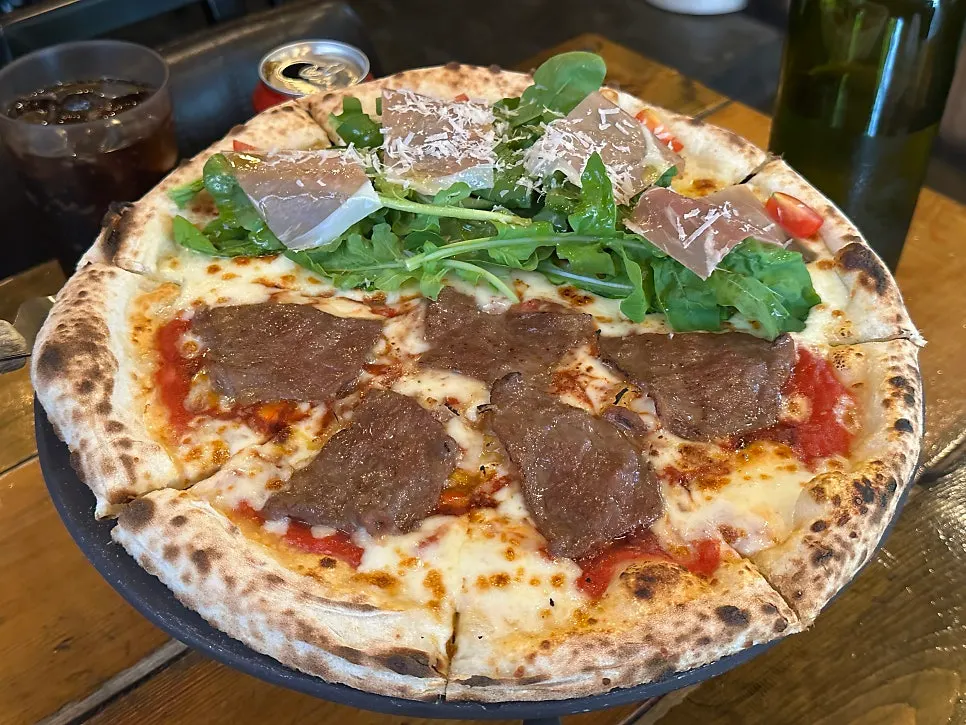 Half-and-half wood-fired pizza with Rucola Prosciutto and Manjo