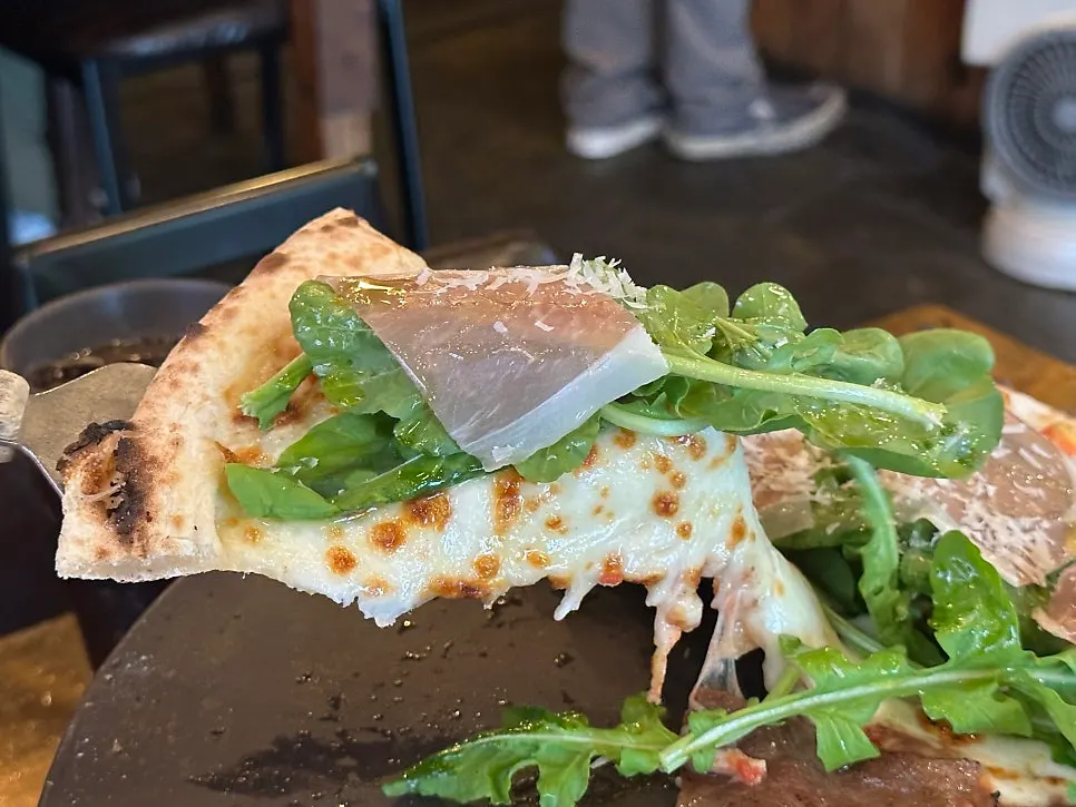 Close-up of rucola and prosciutto toppings on pizza