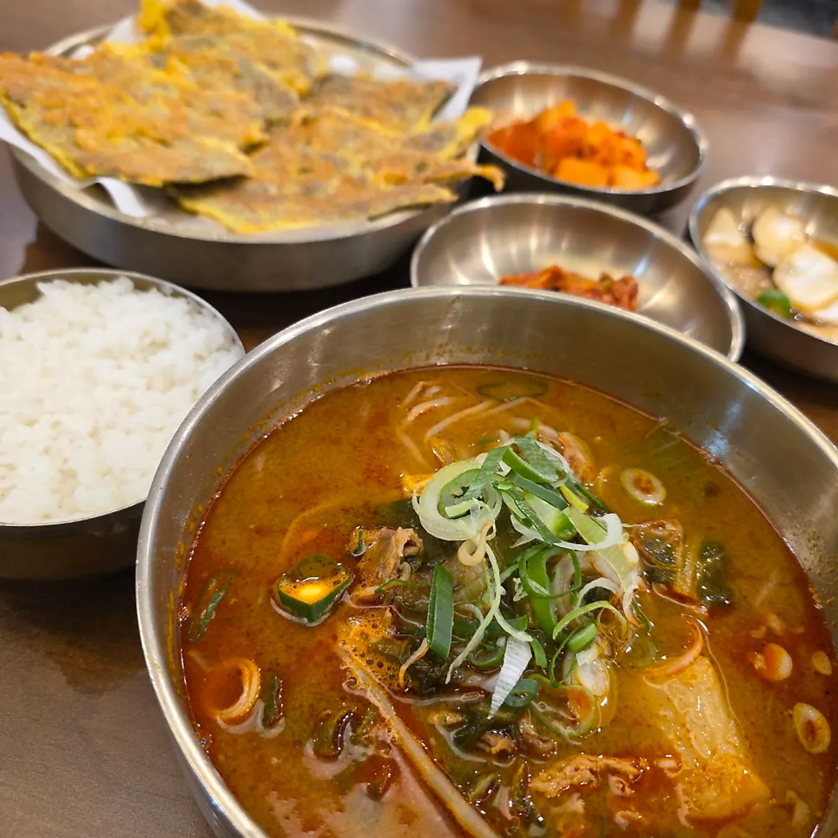 Gukbap piled high with napa cabbage greens, bean sprouts, and green onion