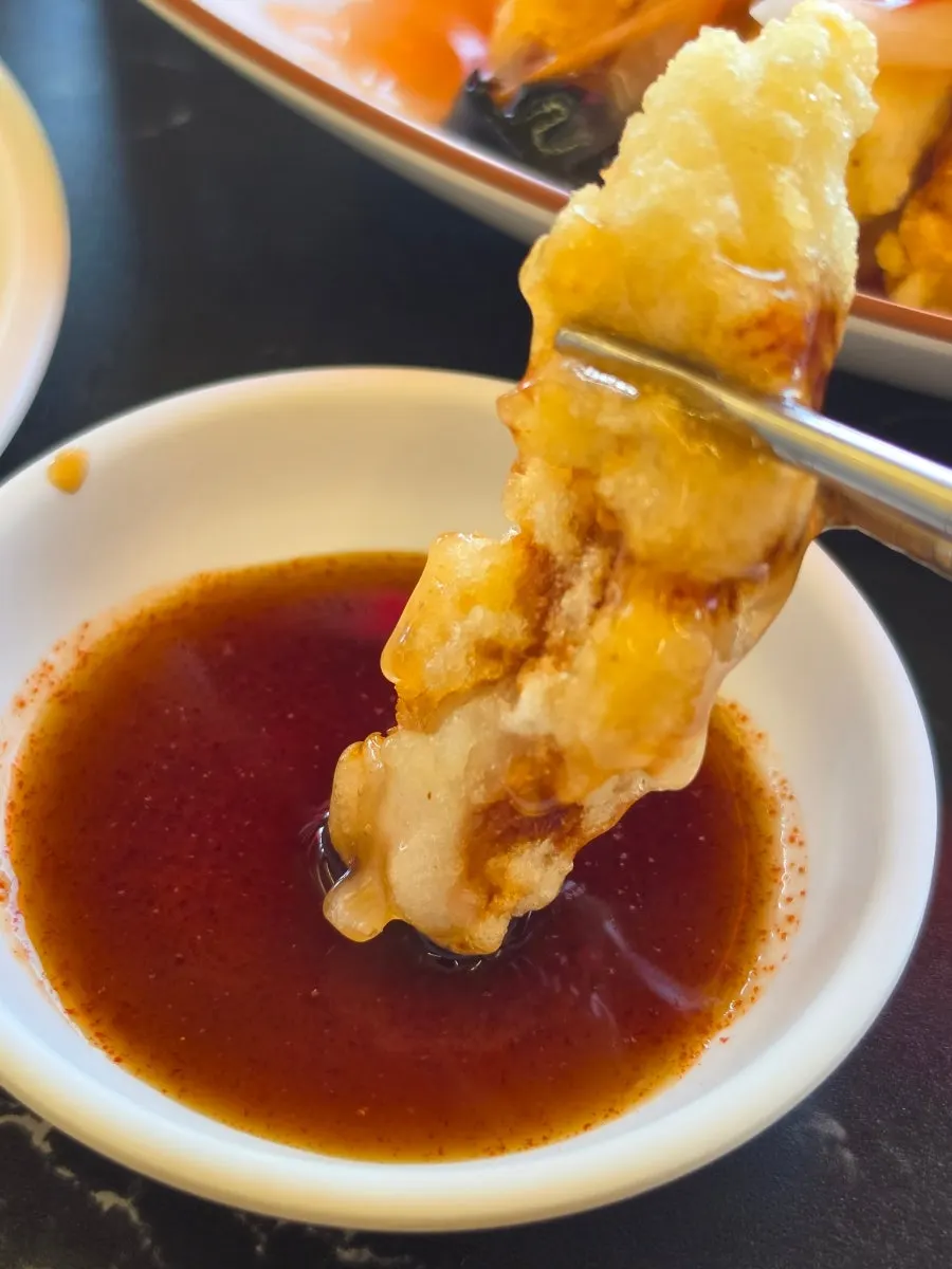A piece of tangsuyuk dipped in soy sauce
