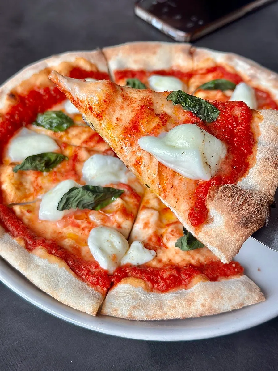 A slice of Margherita pizza topped with chunks of cheese