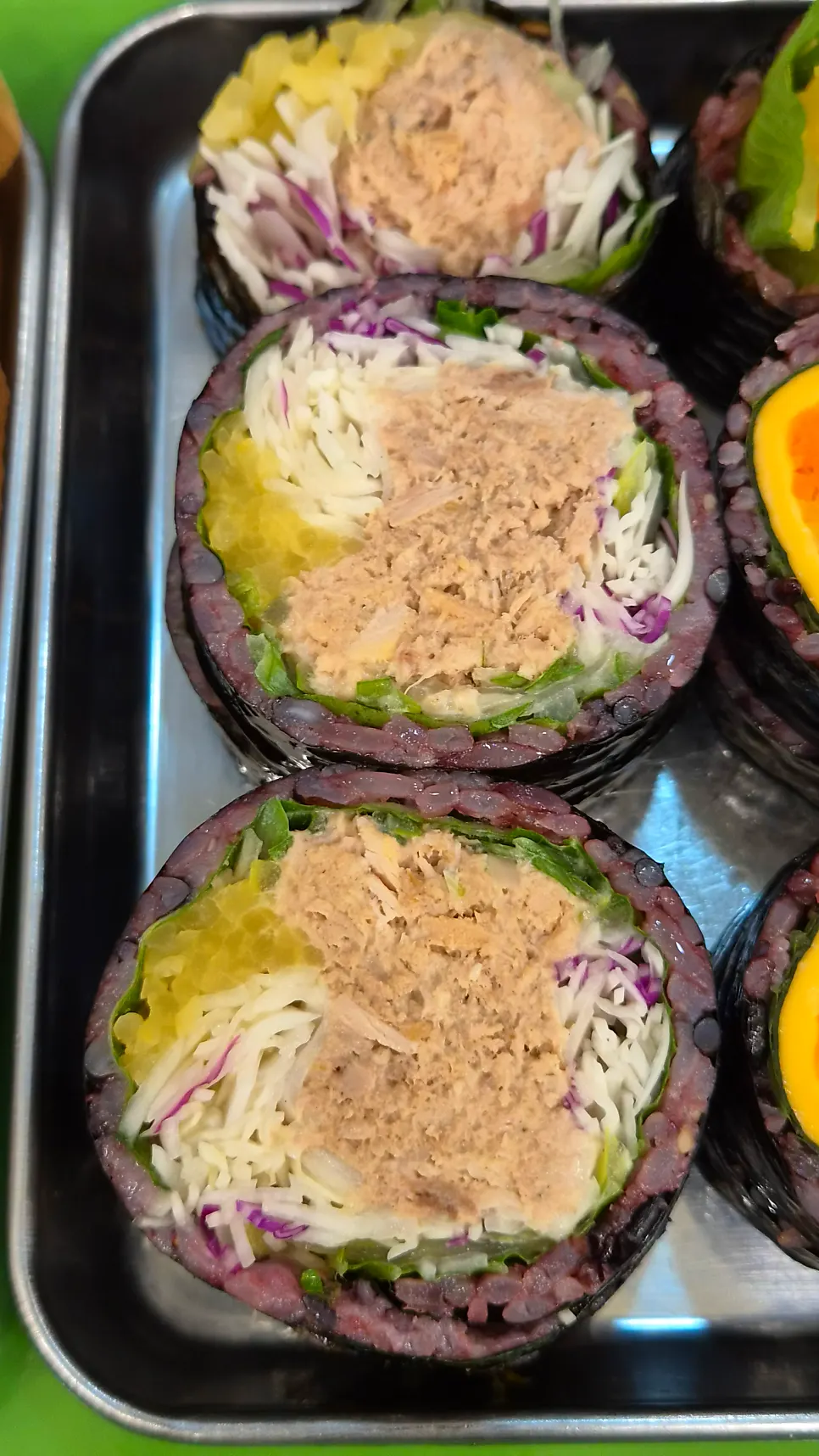 A piece of tuna-scallion gimbap held up