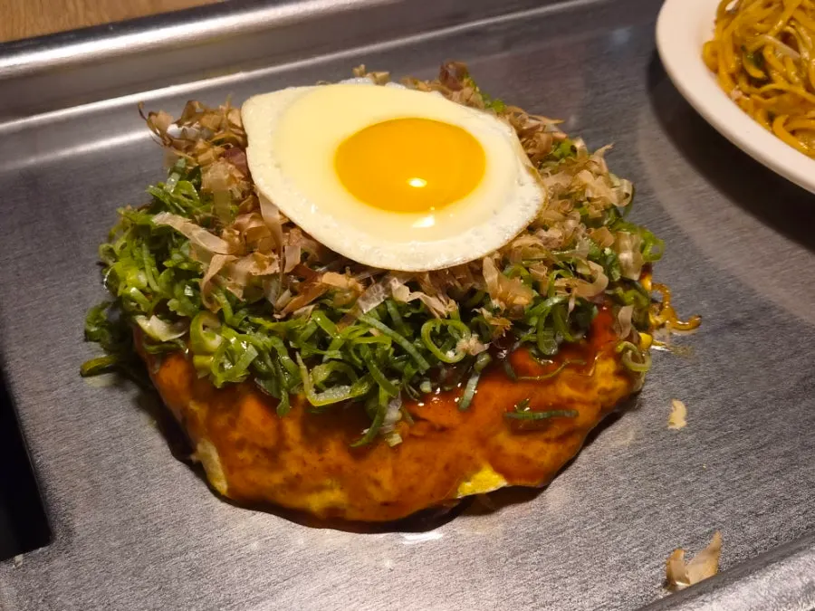 Okonomiyaki plated together with yakisoba on the hot plate