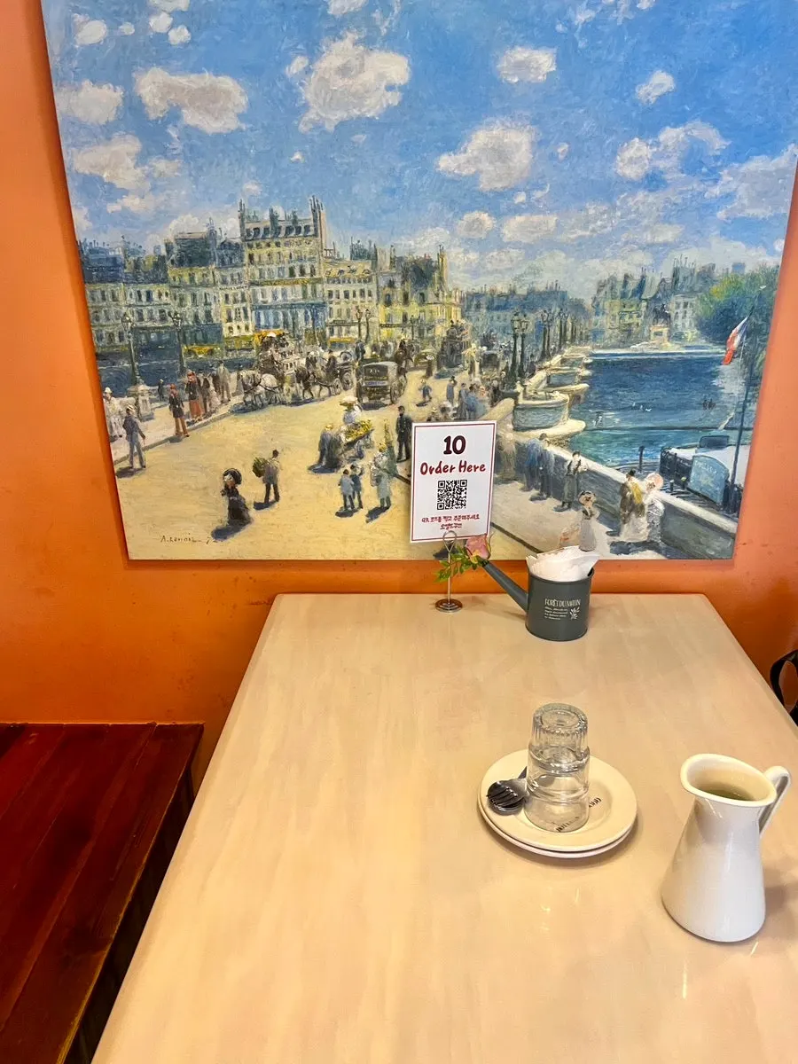 A corner table near the window at Hôtel de Couture with a painting on the wall