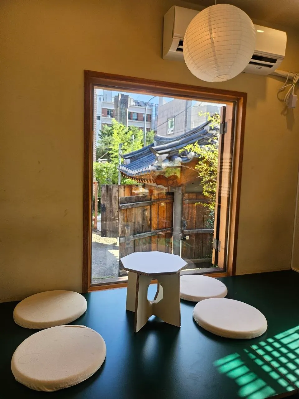 Tempat duduk dalam kafe dengan pemandangan hanok dari tingkap