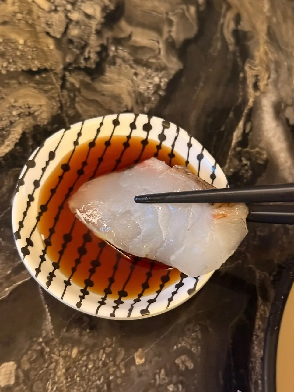 A piece of sashimi dipped in soy sauce
