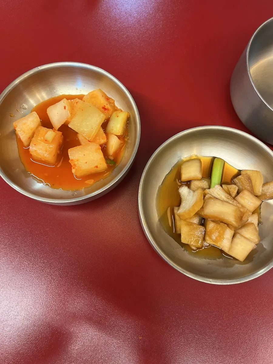 Side dishes of diced radish kimchi and pickled onion