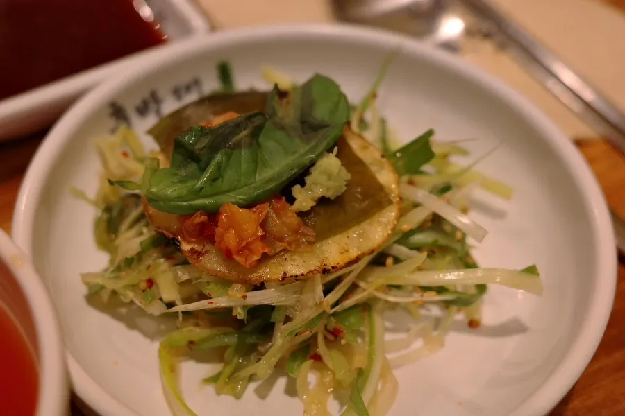 A piece of pork belly topped with basil
