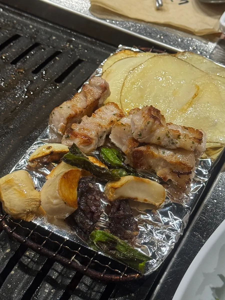다 익은 고기를 올려둔 불판과 소주
