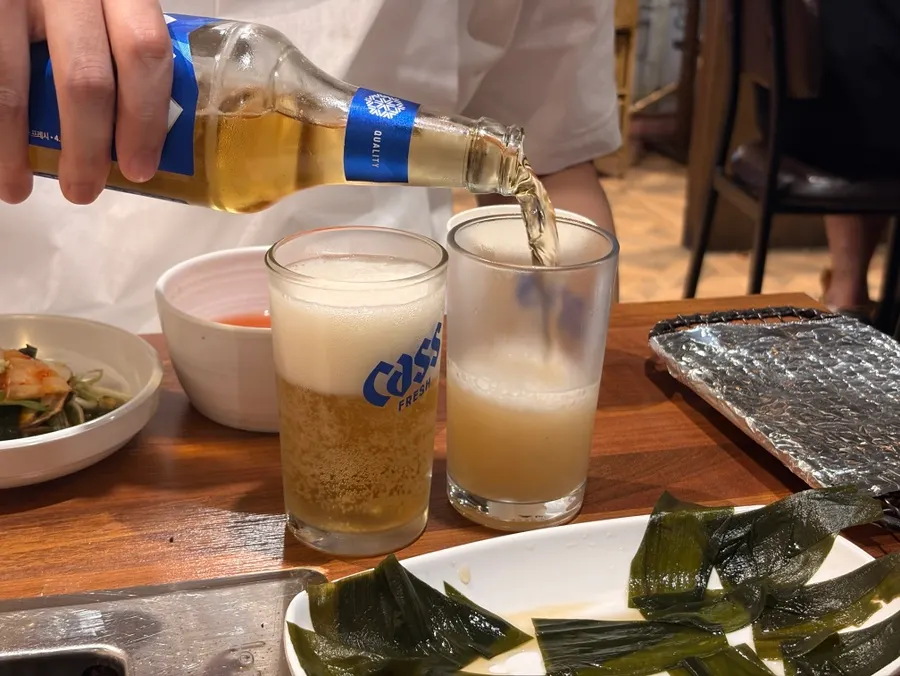 A cold glass of beer alongside the cooking meat