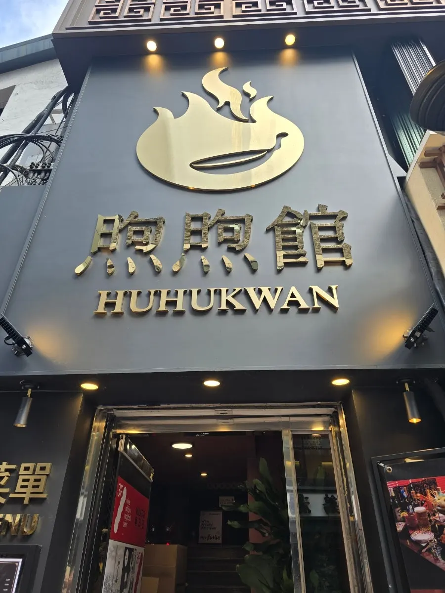Huhugwan's building entrance with a gold logo on a black wall