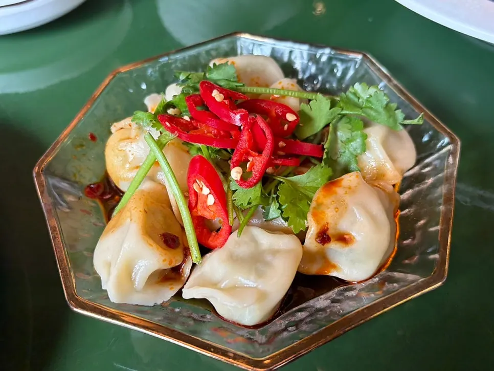 Chinese-style boiled dumplings topped with cilantro and chili oil