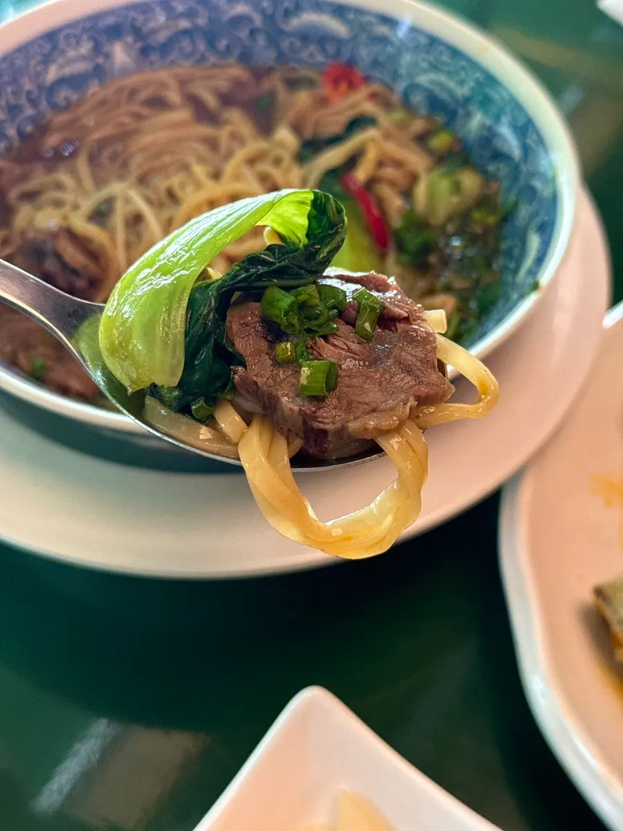 Taiwanese-style beef noodle soup topped with bok choy at Huhugwan