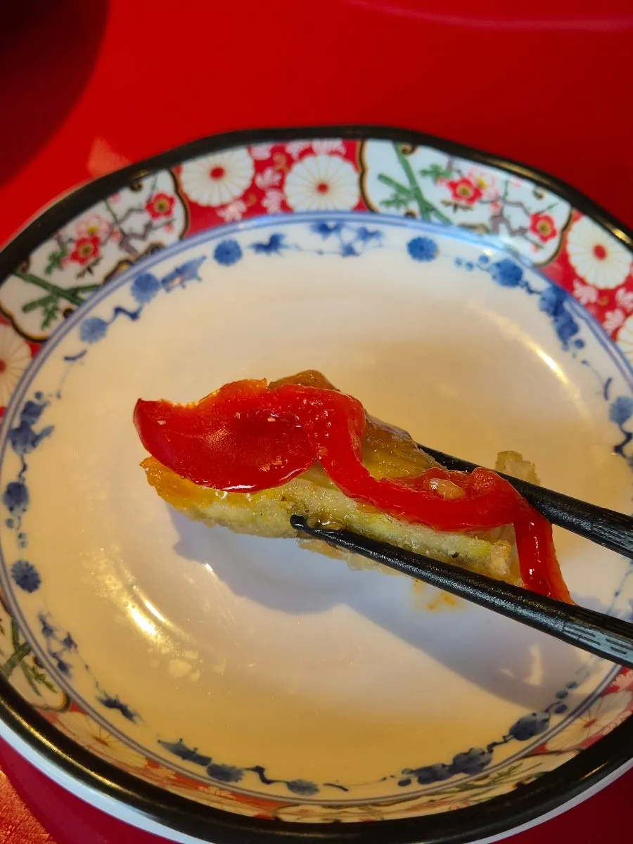 A piece of eggplant fritter dipped in sauce