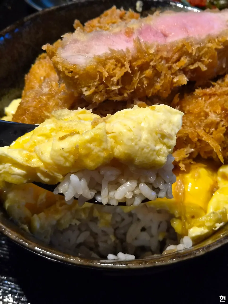 A piece of katsu lifted with chopsticks
