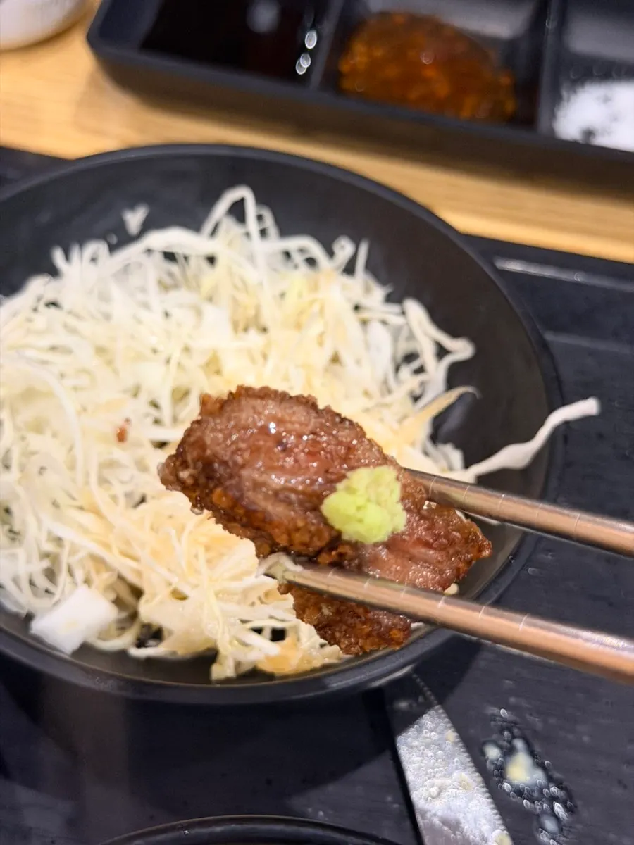 A piece of gyukatsu topped with a small amount of wasabi