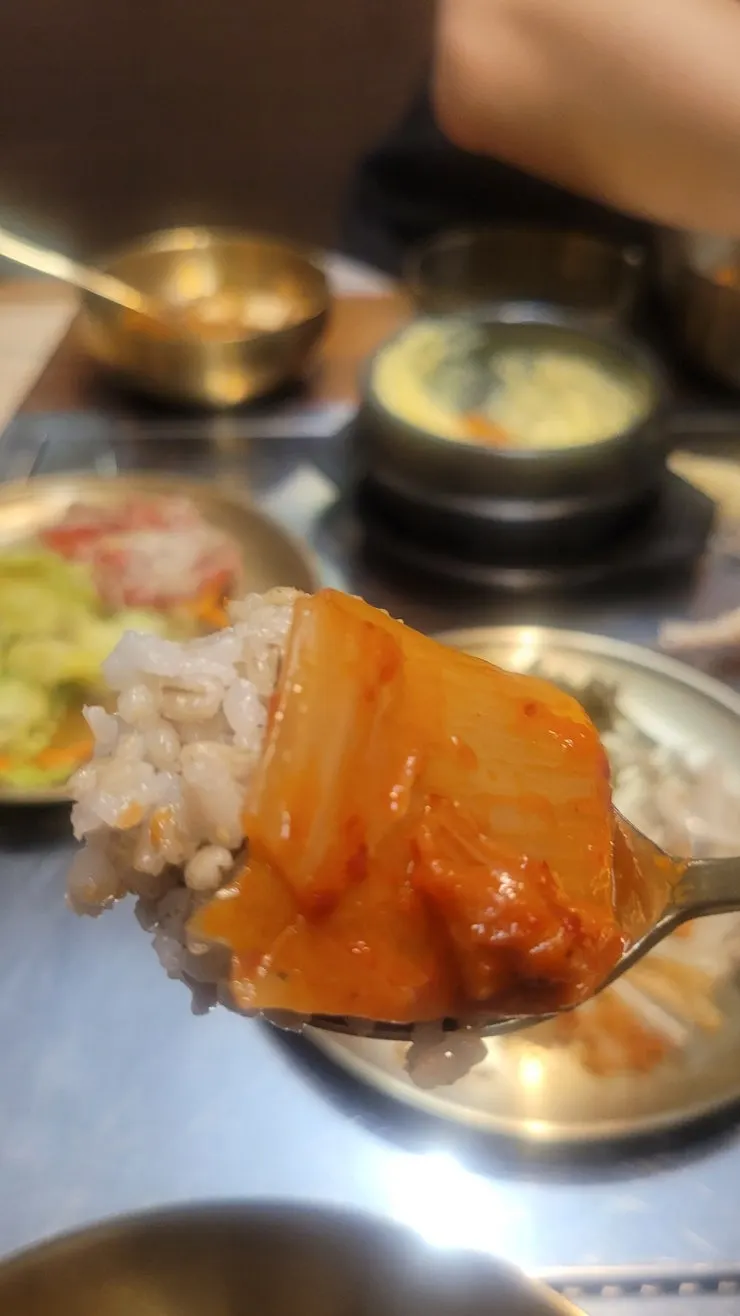 A bite of barley rice with grilled hairtail and kimchi