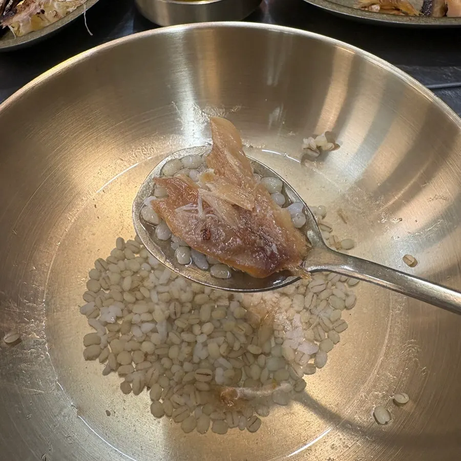 A spoonful of rice in green tea water topped with bori-gulbi