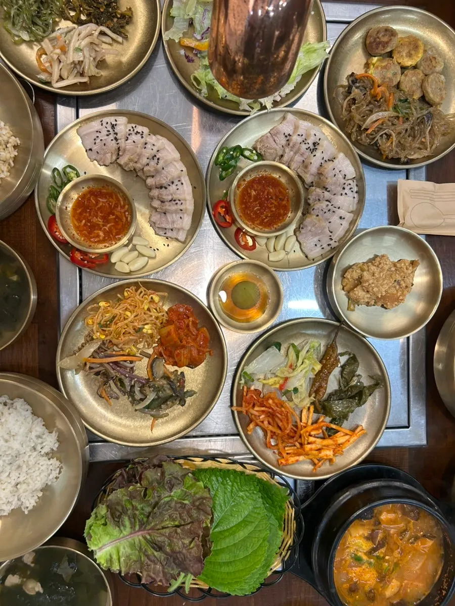 Table with boiled pork, barley rice, and side dishes