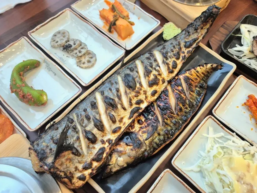 Table with grilled fish, pot rice and side dishes