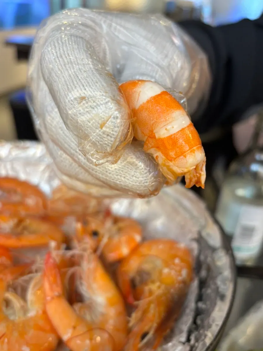 Peeling salt-grilled shrimp shells while wearing gloves