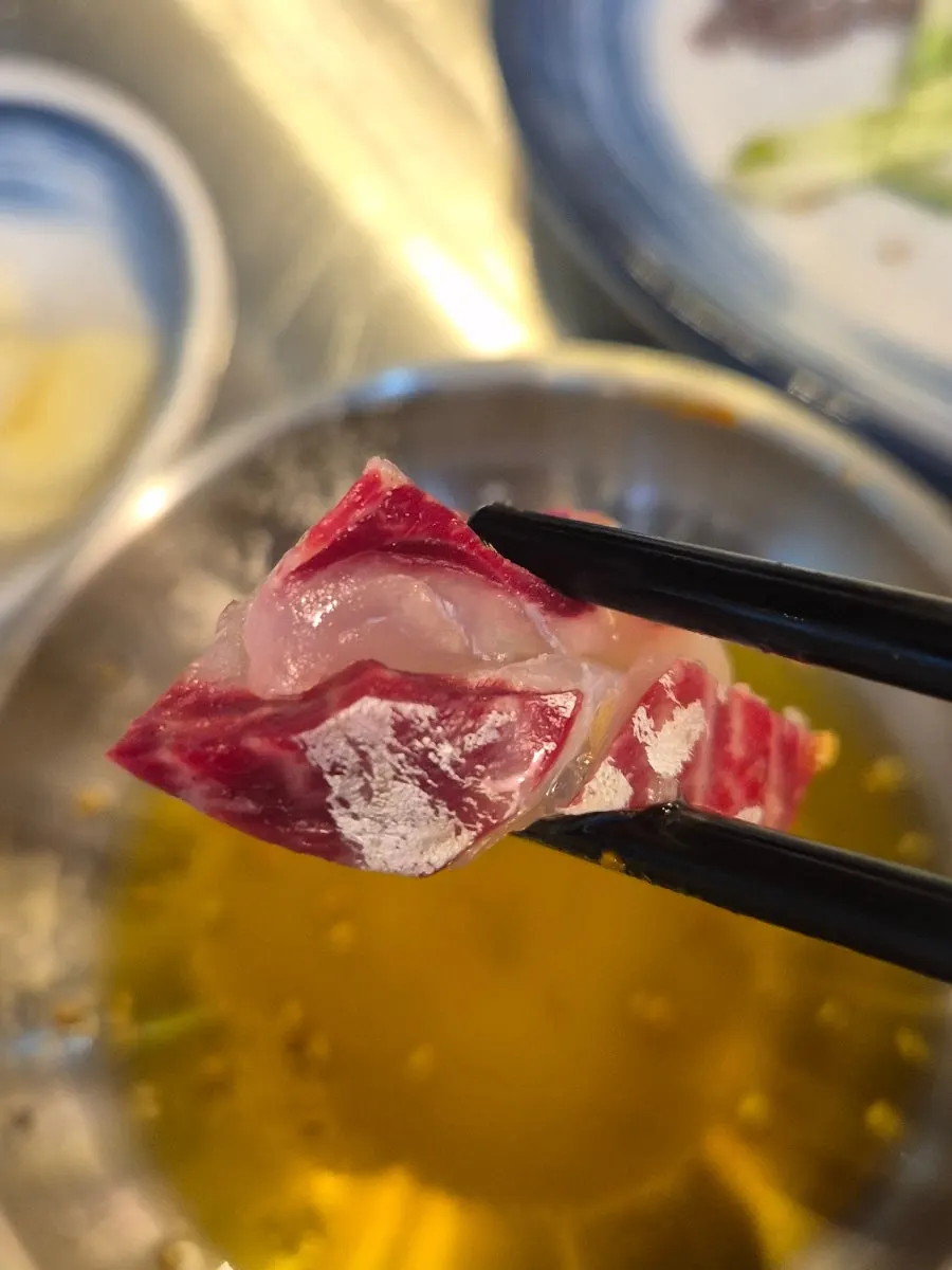 A piece of sashimi dipped in sauce
